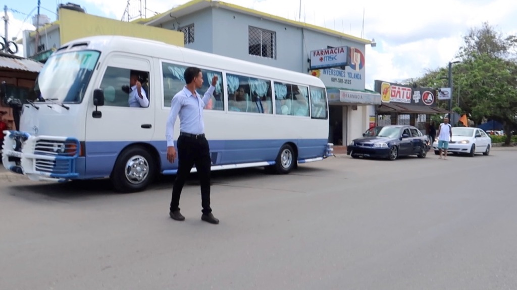 Picture of man directing people into a bus