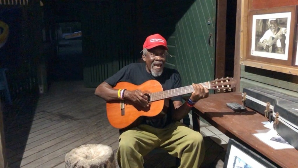 owner of Foxy's bar (Foxy) singing and playing guitar